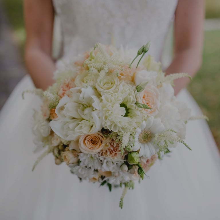 Bride holding white and blush wedding bouquet with roses and peonies