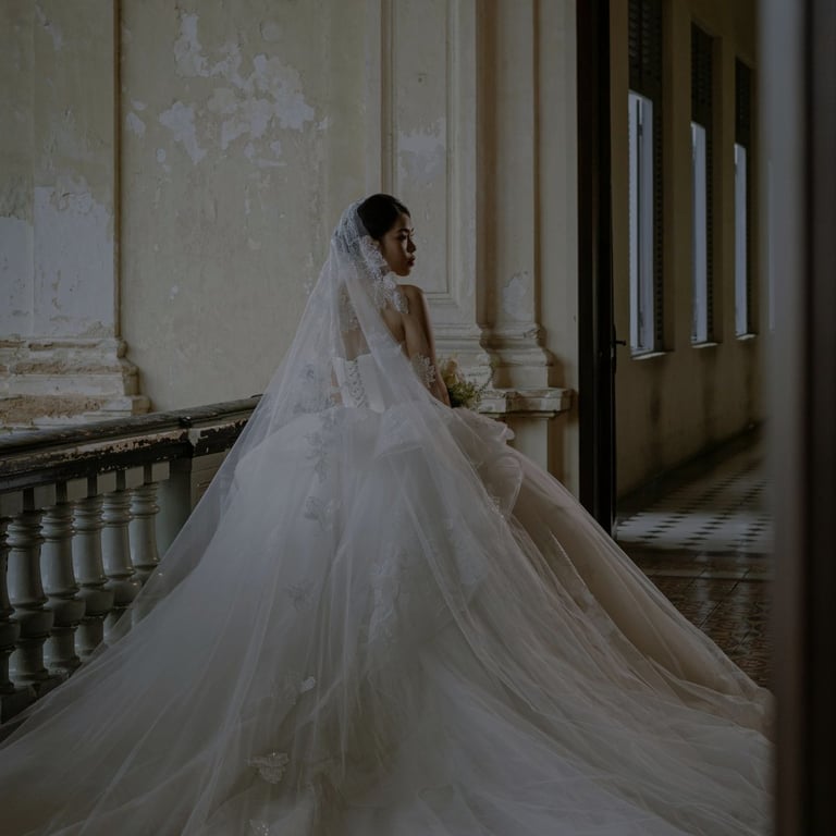 Bride in white wedding dress and veil standing in classical corridor with columns